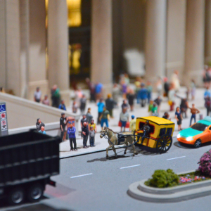 An image of a miniature horse and carriage in front of a building with pillars. There are people standing in the distance.
