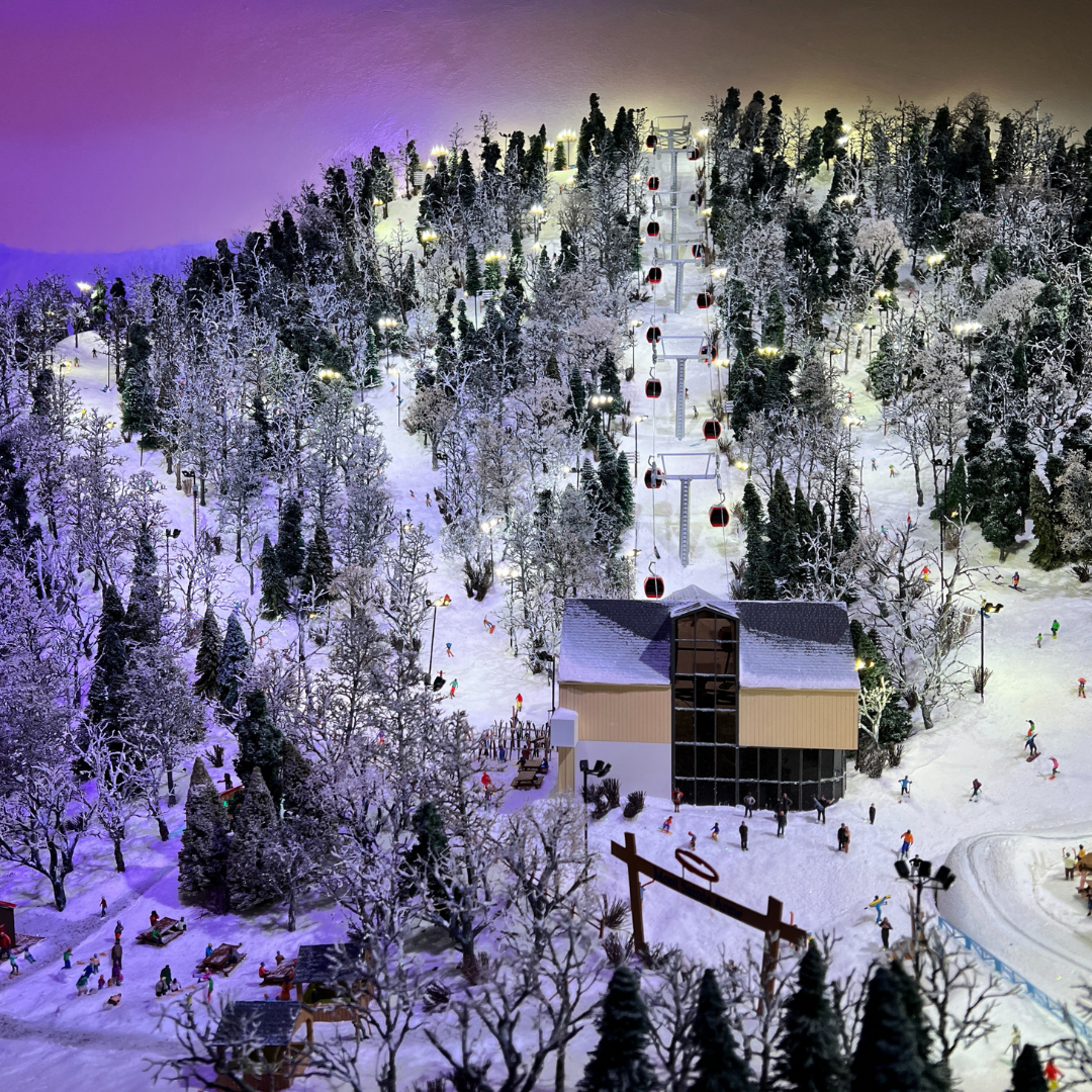 A miniature display of a mountain with tree lined ski slopes.