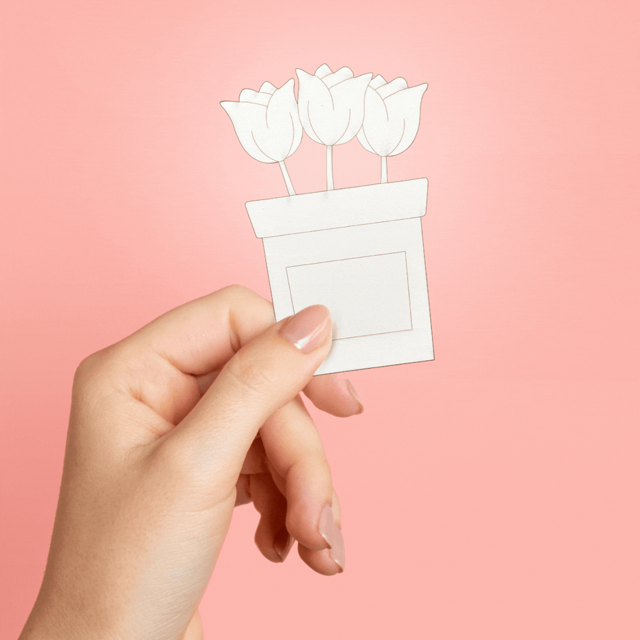A person holding a cutout of three tulips against a pink background.
