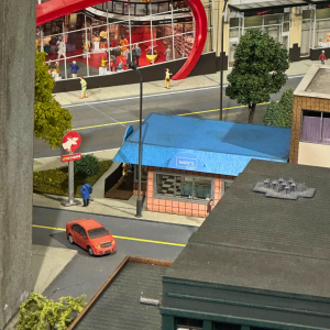A miniature scene of a pink building with a blue roof.