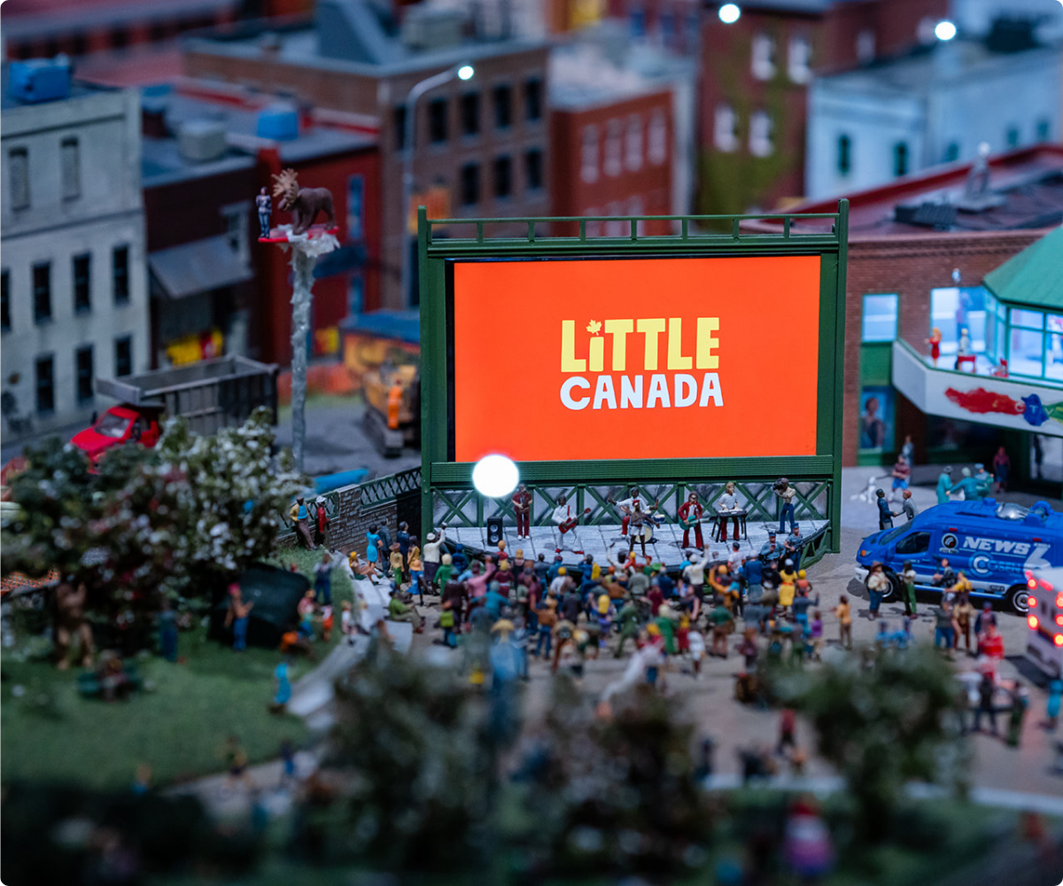 A miniature display of a large screen with a crowd out front watching a performance.