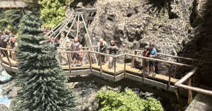 Miniature figures standing on a platform on the edge of a miniature cliff display.